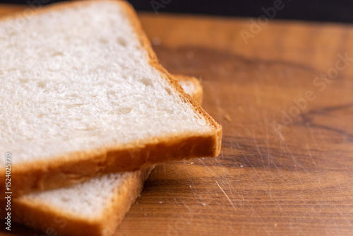 Two slices of garlic bread, their grease minimal, on a wooden board with a subtle shine.