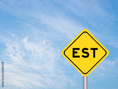 Yellow transportation sign with word EST  (abbreviation of established, estimated, eastern time zone, expressed sequence tag) on blue color sky background
