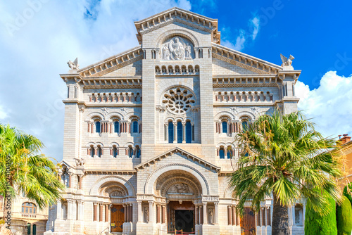 Facade of Monaco Cathedral (Saint Nicholas Cathedral). Palm trees and blue sky in the background, sunny weather