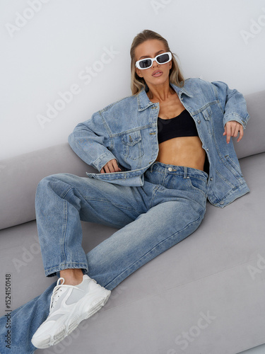 Stylish blonde model poses in denim outfit during indoor photoshoot session