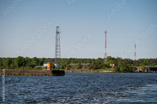 Waterfront view showcasing communication towers and lush greenery on a sunny day