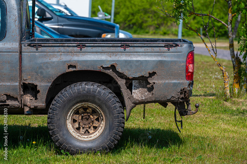 Rusty pickup truck parked in a grassy area on a sunny day