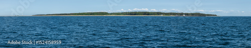 View of a peaceful coastline with lush greenery and calm blue waters on a sunny day
