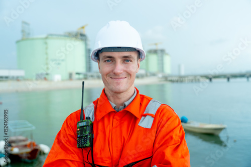 Portrait of petrochemical worker or technician stand with arm-crossed with smiling in front of factory tank.