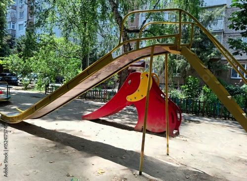 playground in the park. slides for children in the courtyard of the house.
view of the playground with two slides, one of them is high metal, the other is smaller in the form of a red elephant for sma