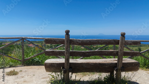 Scenic viewpoint with a weathered wooden bench offering breathtaking views of the Tyrrhenian Sea in Calabria, Southern Italy