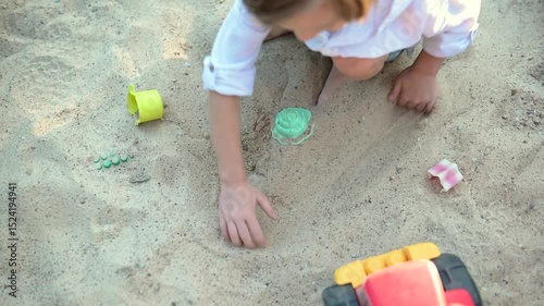 Adorable little boy having fun on a playground on bright sunny summer day. Cute child playing in a sandbox. Summer outdoor activities for family with kids.