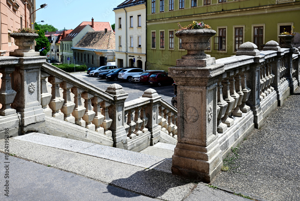 Fototapeta premium old style stone stairs and balustrade in urban downtown area. colorful classic stucco exterior elevations with windows. carved stone guard rail. travel and tourism concept. blue sky. summer scene.