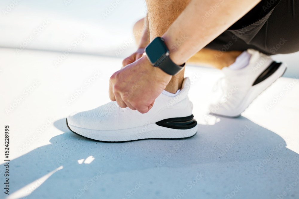Naklejka premium Lacing up White Sneakers Before an Early Morning Run on a Sunny Day in a Vibrant Urban Setting
