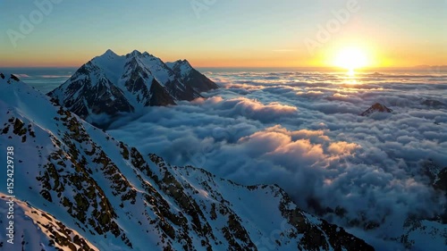 mountains covered in snow and clouds with a sun setting in the distance