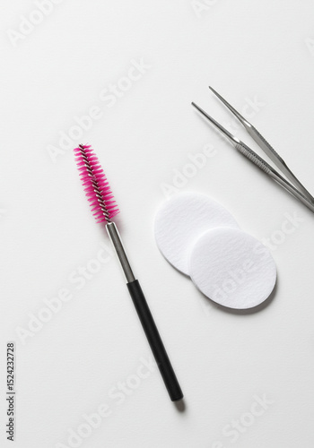 Eyelash Extension Tools: Spoolie Brush, Tweezers, and Eye Pad on White Background