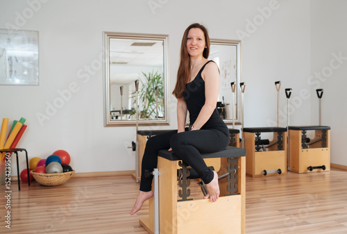 Beautiful fit-shape female dressed sporty sitting and sincerely smiling in sport athletic gym. Active people training or medical rehabilitation concept image