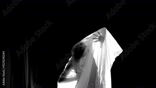 Young dancer performing under white veil in black and white. Selective focus