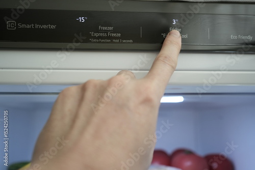 A man's hand adjusts the temperature of the refrigerator and freezer. Close-up. Modern gray stylish refrigerator. Optimal food storage temperature. High quality photo