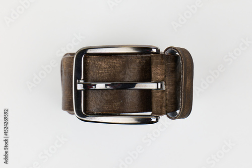 A brown leather belt with a shiny silver buckle placed on a white background