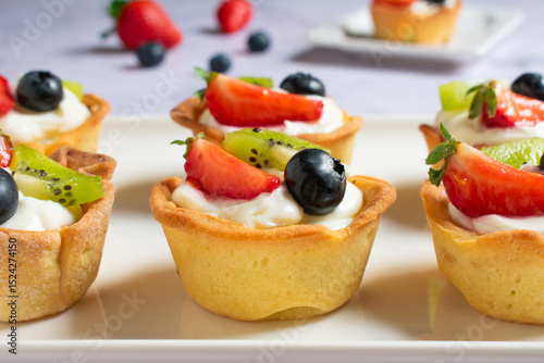 Tartaletas de crema de queso y fruta fresca en bandeja de cerámica blanca