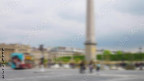 Double-decker tourist bus passes through the Place de la Concorde square with views of the Obelisque de Louxor, Hotel de la Marine and the Jardin des Tuileries. Out of focus. Paris, France.