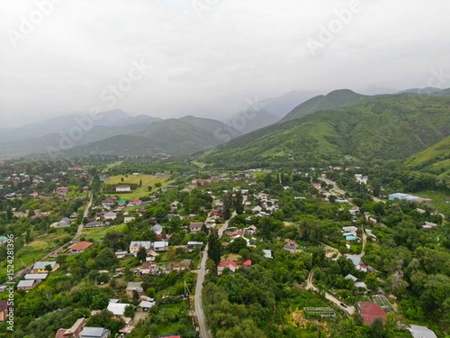 A village on the outskirts of the city. Hilly terrain with different vegetation. The view from the drone.