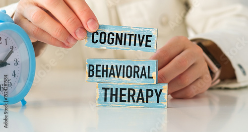 A person is holding a blue block with the word Cognitive Behavioral Therapy
