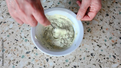The homemaker prepares the condiment by blending mayonnaise and seasonings.