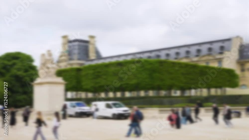 People strolling in the Place du Carrousel with a view of the Statue La France Victorieuse and the Jardin du Carrousel on a clear sunny spring day. Out of focus. Paris, France.