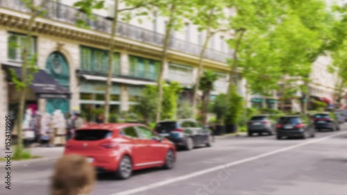 Picturesque street with busy traffic of cars and cyclists, beautiful architecture on a sunny spring day in the 1st arrondissement. Out of focus. Paris, France.