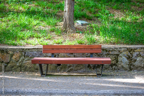 Modern wooden bench in a park. Sitting, resting place in nature. Quiet, calm, peaceful. Seat. 