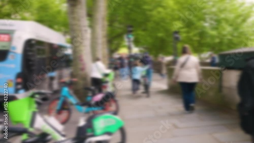 View of transport driving along Quai de la Megisserie, people walking along the street and bicycles for rent. Out of focus. Paris, France.