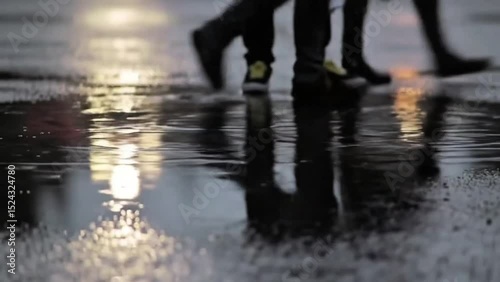 Rainy day reflections on wet pavement, capturing the essence of urban life during a downpour. The focus is on the legs and footwear of pedestrians, creating a unique perspective.