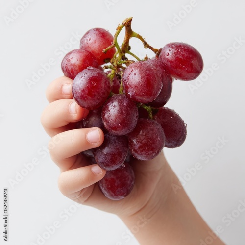 Hand of a young child clasping dew-kissed grapes, evoking Dionysian revelry; harvest festival and Sukkot essence