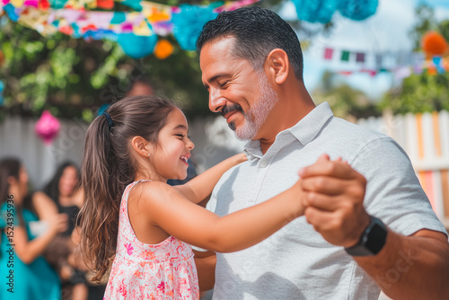 Hispanic father and daughter dancing at a party in the backyard