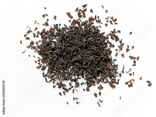 Loose black tea leaves scattered on a white surface showcasing their rich texture and deep color