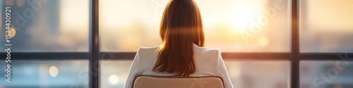 A woman is sitting in a chair looking out the window at the sun