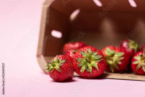 Frische Erdbeeren in Pappschale auf rosa Hintergrund 
