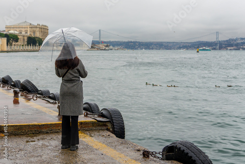 Photography A young girl with umbrellas in their hands look out over the Bosphorus Bridge in