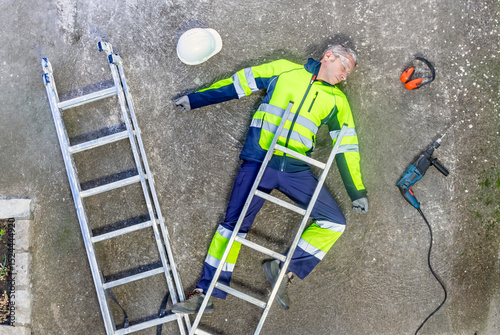 Top view of a construction worker lying unconcious after a workplace accident. Ppe for Safety at work. photo