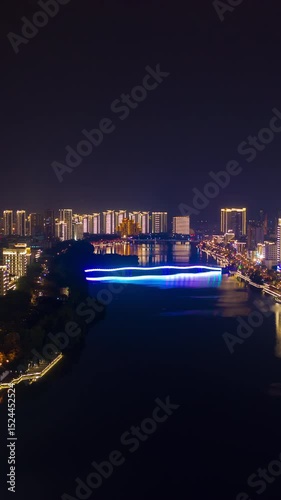 night time illumination sanya city river traffic bridge aerial vertical panorama timelapse 4k china