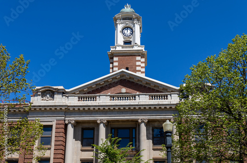 Low angle view of an exterior cupola and clock tower on a exterior brick building in bright sunlight with blue sky