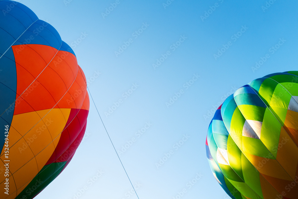Fototapeta premium Two Colorful Hot Air Balloons Against a Clear Blue Sky