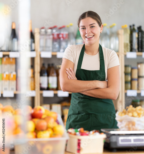 Wallpaper Mural Young female seller in apron standing at counter in grocery store Torontodigital.ca