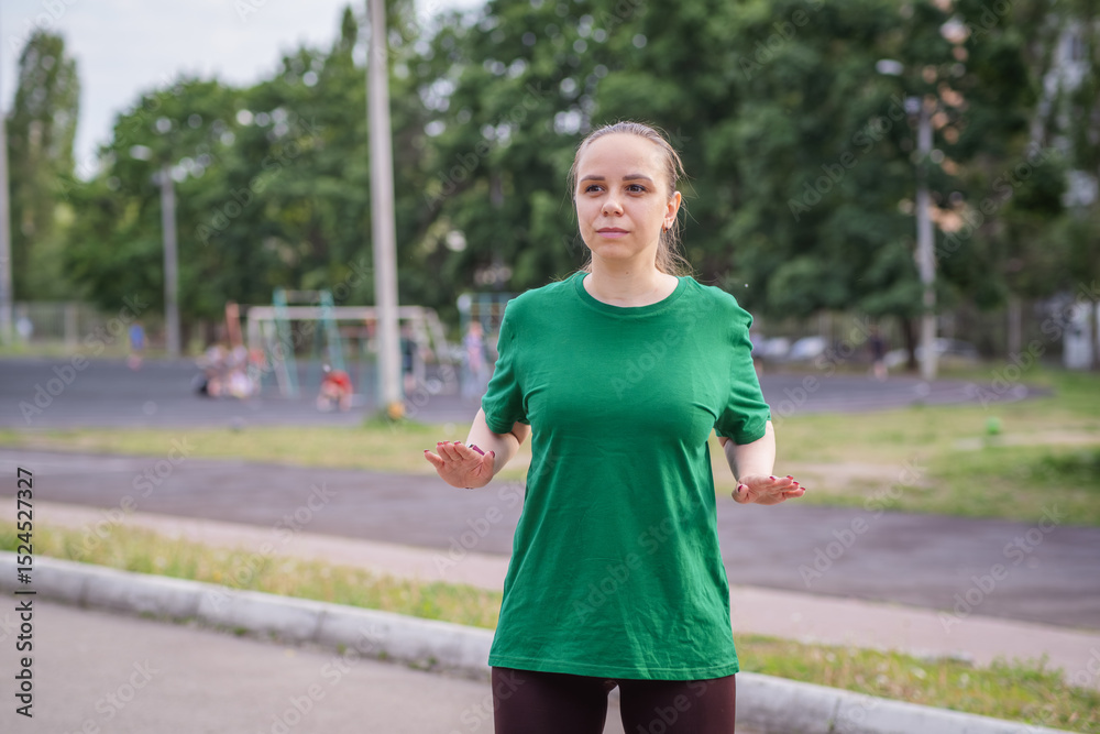 Young woman stretching in a green shirt during outdoor workout Young woman stretching in a green shirt during outdoor workout