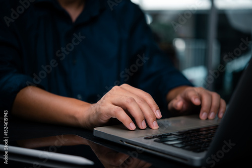 Close-up of hands typing on laptop in a dark workspace. Concept of work focus, remote job, or programming technology digital transformation, and smart work solutions. photo