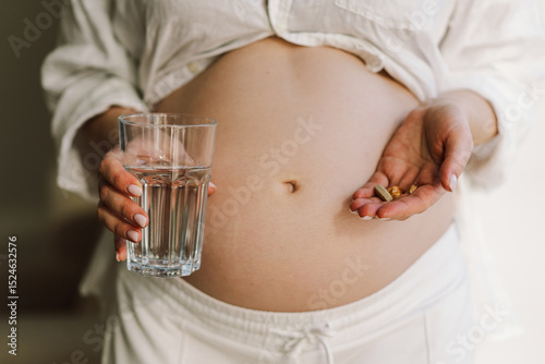 Pregnant young woman holding vitamins to maintain health of herself and her baby. Pregnancy and Health Concept