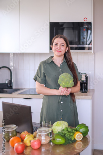 Woman holding broccoli in kitchen. Cooking, recipes, cooking, vegetarianism, healthy eating