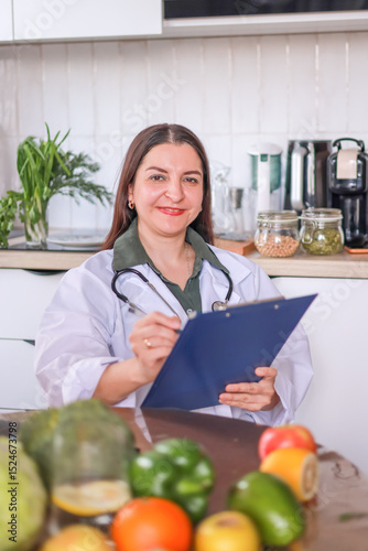 Female nutritionist at a table with healthy food tablet for notes. Health, medical services concept.