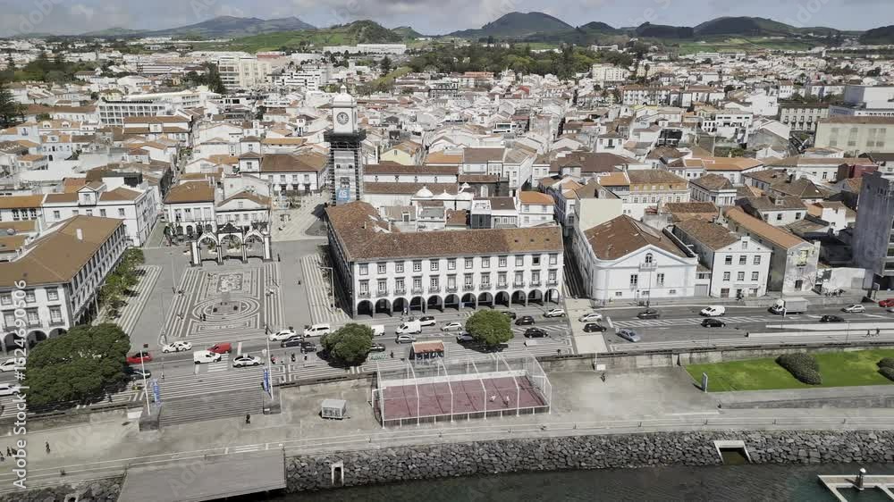 Drone flies to right from Portas da Cidade, facing north and following Avenida Infante Dom Henrique on sunny day in Ponta Delgada, Sao Miguel, Azores, Portugal