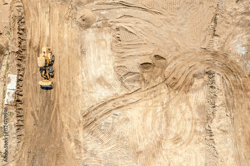 heavy earthmover working at earthworks at a construction site. flattening ground. aerial top view.