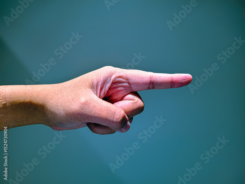 Close-up of a hand pointing with the index finger to the right against a solid blue background, symbolizing direction, instruction, or attention.