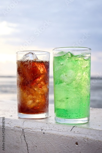 Green and cola soft drink and ice cubes photo