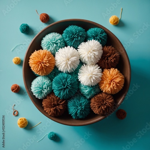 Colorful yarn pom poms overflowing in brown bowl on turquoise surface
